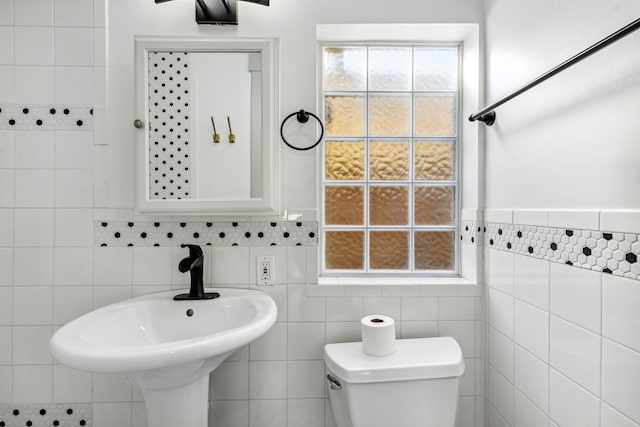 bathroom featuring toilet and tile walls