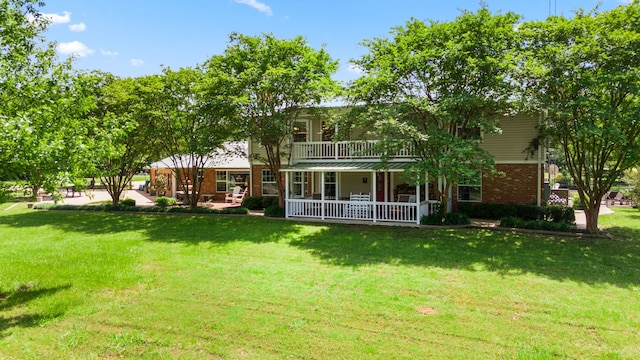 rear view of property with covered porch, a yard, brick siding, and a balcony
