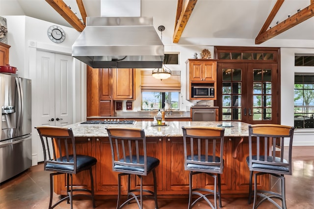 kitchen with island exhaust hood, lofted ceiling with beams, stainless steel appliances, and plenty of natural light