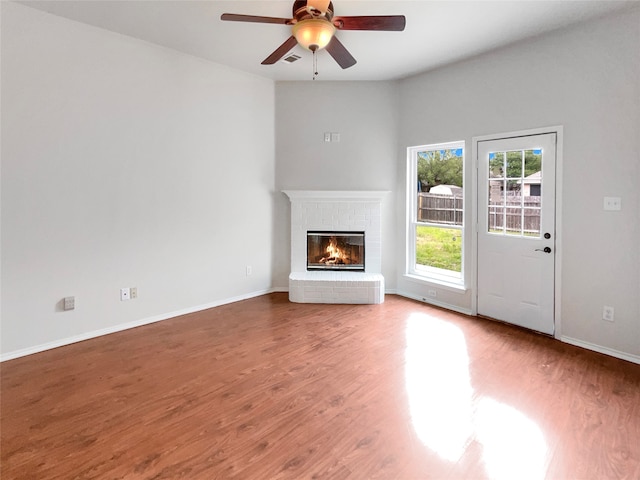 unfurnished living room featuring a brick fireplace, ceiling fan, and hardwood / wood-style flooring