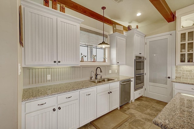 kitchen featuring appliances with stainless steel finishes, beamed ceiling, white cabinetry, sink, and hanging light fixtures