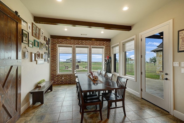 dining room with brick wall, a barn door, and beamed ceiling