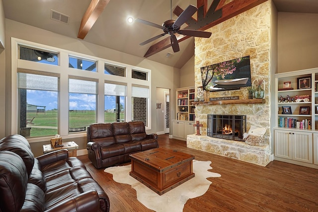 living room with a stone fireplace, high vaulted ceiling, hardwood / wood-style flooring, ceiling fan, and beam ceiling