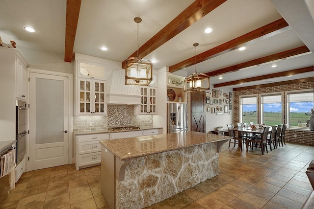 kitchen with white cabinetry, a kitchen island, decorative light fixtures, and appliances with stainless steel finishes