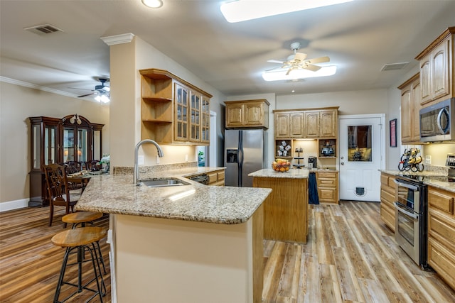 kitchen with a center island, appliances with stainless steel finishes, kitchen peninsula, sink, and ceiling fan