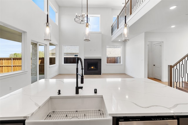 kitchen featuring a tile fireplace, a wealth of natural light, dishwasher, sink, and decorative light fixtures