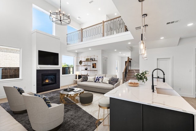 living room featuring light hardwood / wood-style floors, a tile fireplace, sink, and a high ceiling