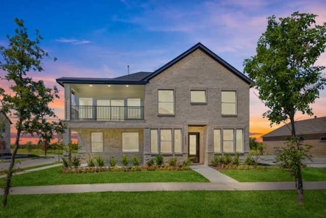 view of front of home with a balcony and a lawn