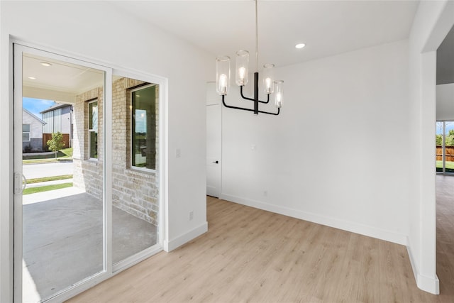 unfurnished dining area featuring light hardwood / wood-style floors and a notable chandelier