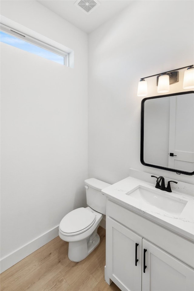 bathroom with hardwood / wood-style floors, vanity, and toilet