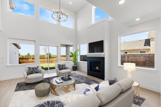 living room with light hardwood / wood-style floors, a high ceiling, and an inviting chandelier