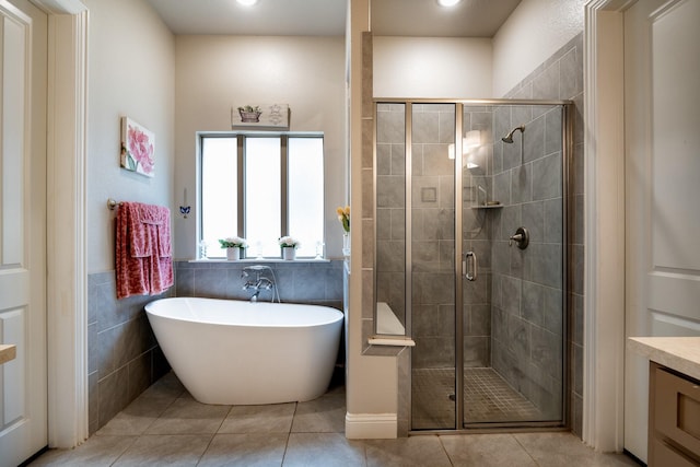 bathroom with a stall shower, a soaking tub, tile walls, and tile patterned floors