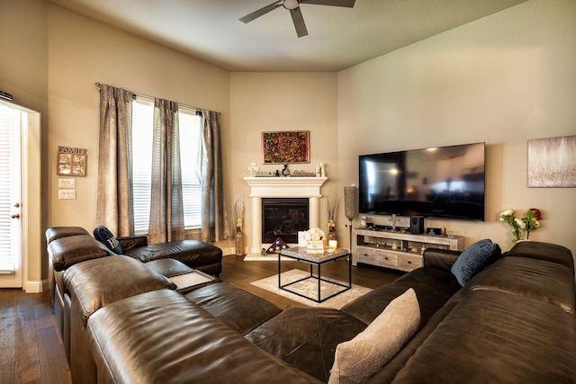 living area featuring dark wood-style floors, ceiling fan, and a glass covered fireplace