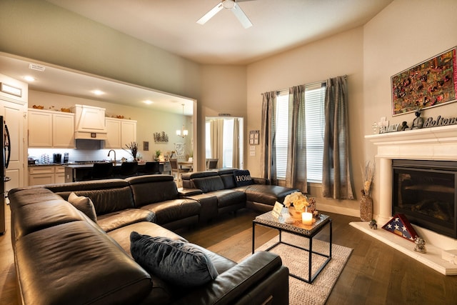 living room with baseboards, visible vents, a ceiling fan, a glass covered fireplace, and dark wood-style flooring