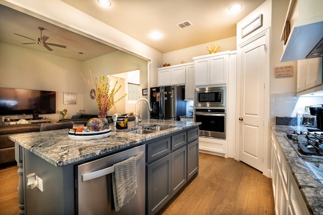 kitchen featuring visible vents, white cabinets, an island with sink, stainless steel appliances, and a sink