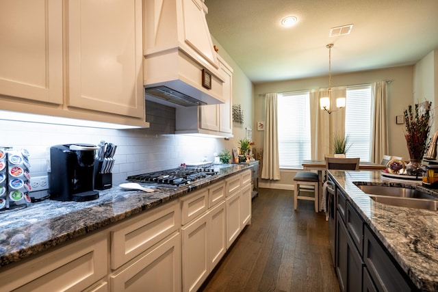 kitchen featuring white cabinets, stainless steel gas stovetop, decorative light fixtures, and dark stone countertops