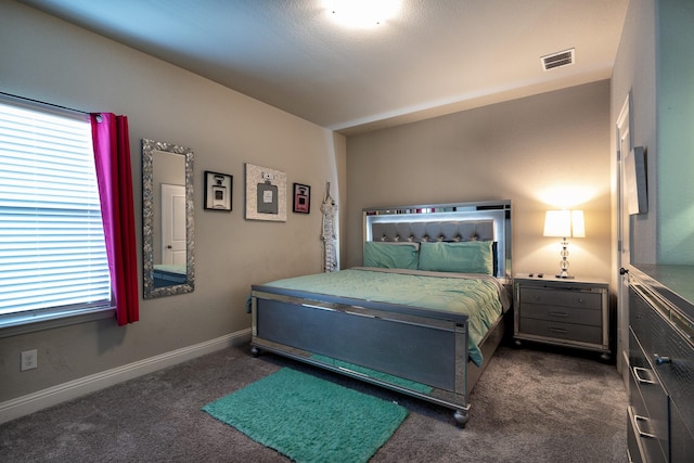 bedroom with dark colored carpet, visible vents, and baseboards