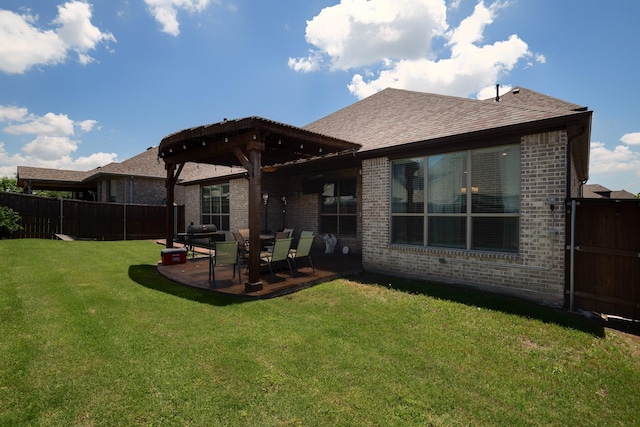 back of house with brick siding, a yard, a shingled roof, a patio area, and fence