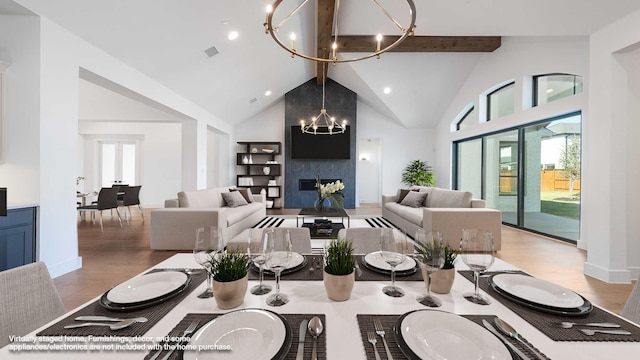 dining room featuring beam ceiling, wood-type flooring, a notable chandelier, and a fireplace