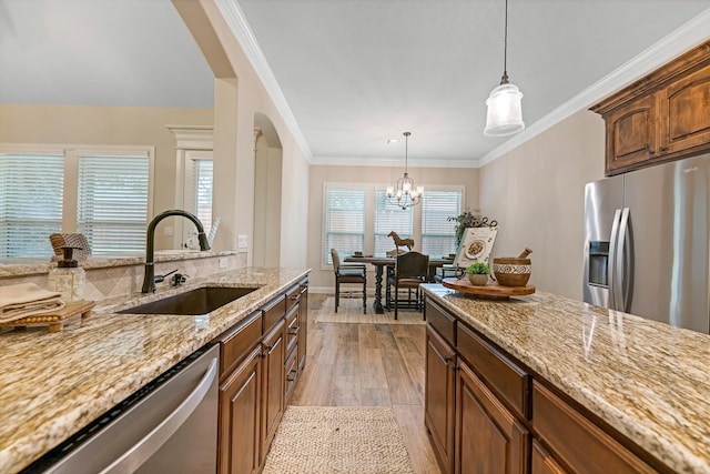 kitchen featuring crown molding, light wood-type flooring, appliances with stainless steel finishes, pendant lighting, and sink