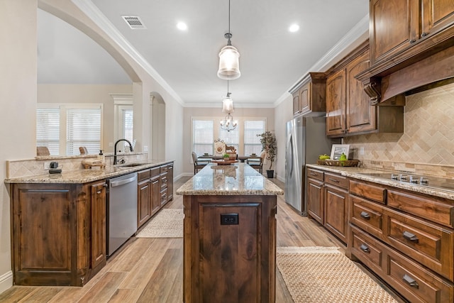 kitchen featuring light stone countertops, dishwasher, light wood-type flooring, a kitchen island, and sink