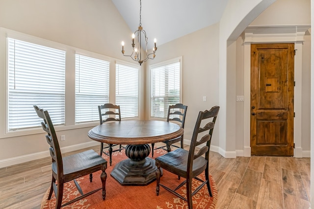 dining room with light hardwood / wood-style floors, lofted ceiling, and a notable chandelier