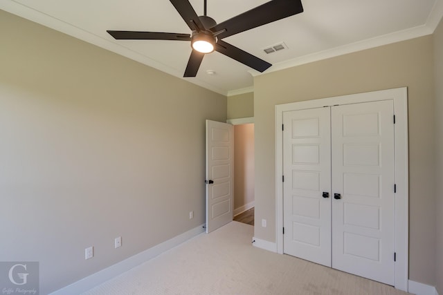 unfurnished bedroom featuring ceiling fan, ornamental molding, a closet, and light colored carpet