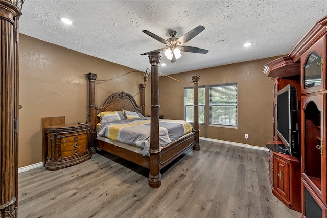 bedroom with hardwood / wood-style flooring, ceiling fan, and a textured ceiling