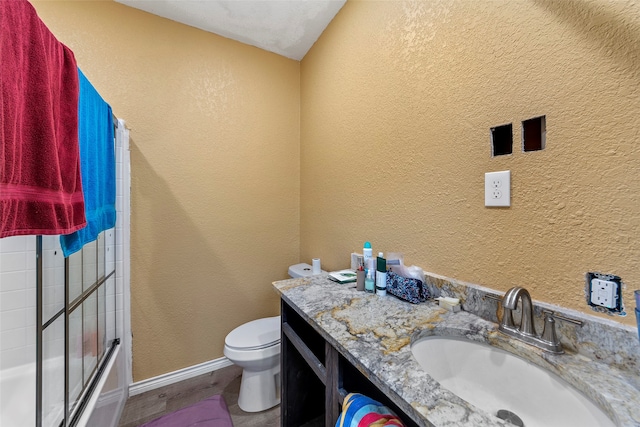 full bathroom featuring combined bath / shower with glass door, toilet, and vanity