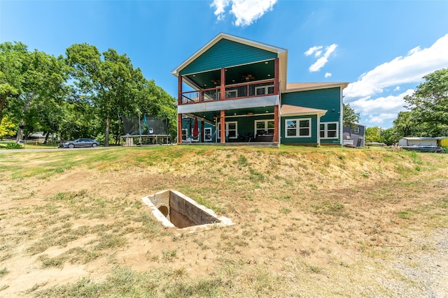 rear view of house featuring a lawn and a trampoline