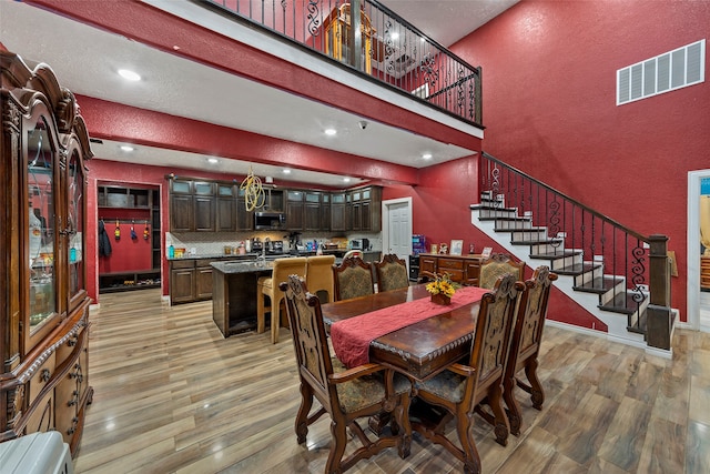 dining room featuring a towering ceiling and light hardwood / wood-style flooring