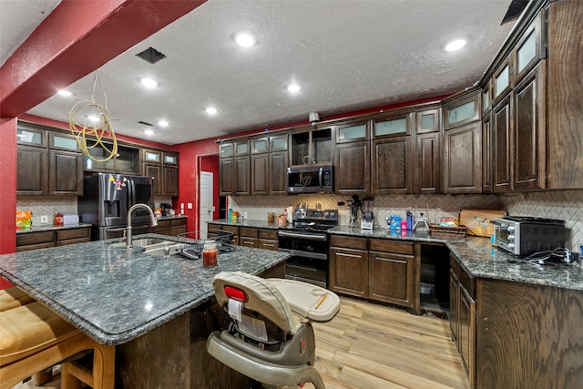 kitchen featuring stainless steel appliances, backsplash, and a kitchen island with sink