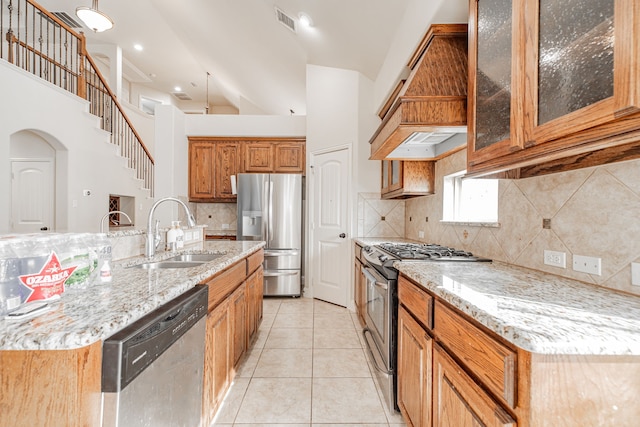 kitchen with custom range hood, appliances with stainless steel finishes, sink, tasteful backsplash, and light tile floors