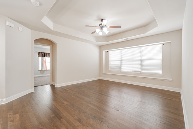 spare room featuring dark wood-type flooring, ceiling fan, and a tray ceiling