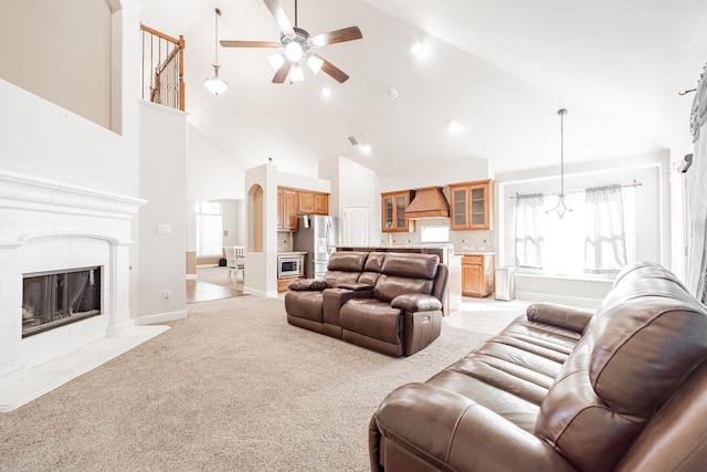 living room with high vaulted ceiling, ceiling fan, a healthy amount of sunlight, and light carpet