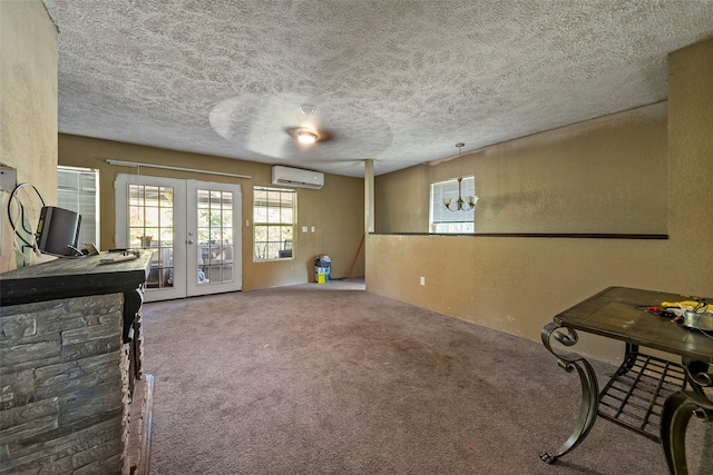 interior space with french doors, carpet, a textured ceiling, and a wall mounted air conditioner