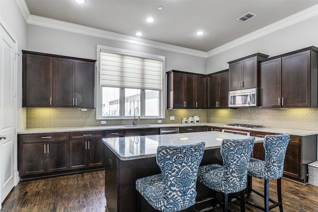 kitchen featuring dark hardwood / wood-style flooring, stainless steel appliances, tasteful backsplash, a center island, and sink