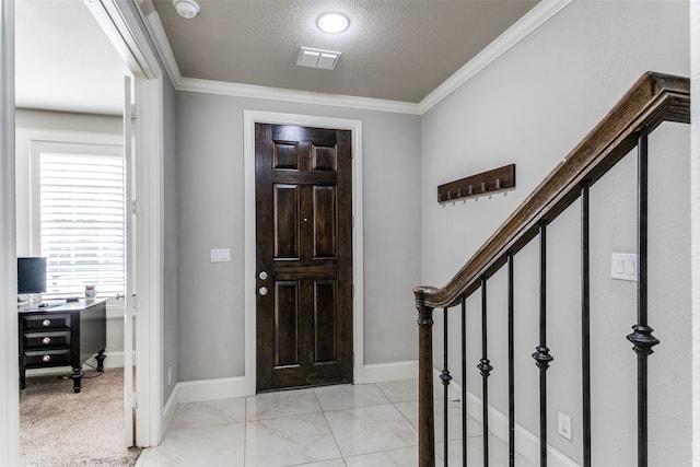 tiled foyer featuring a textured ceiling and crown molding