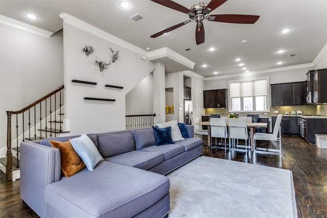 living room with dark hardwood / wood-style floors, ceiling fan, crown molding, and sink