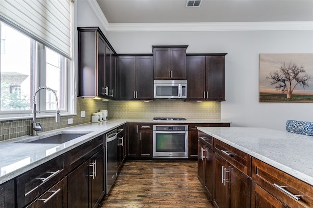 kitchen featuring tasteful backsplash, light stone countertops, dark wood-type flooring, appliances with stainless steel finishes, and sink