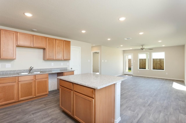 kitchen featuring a kitchen island, dark hardwood / wood-style floors, sink, ceiling fan, and light stone countertops