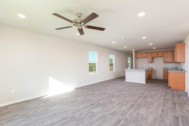 unfurnished living room featuring ceiling fan, sink, and light hardwood / wood-style floors