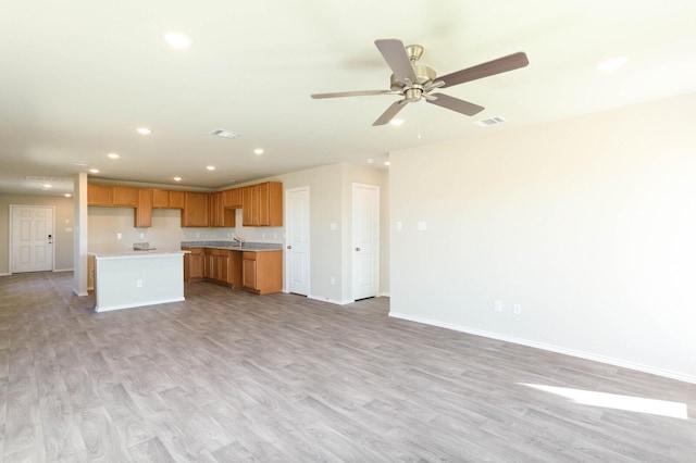 kitchen featuring ceiling fan, a kitchen island, sink, and light hardwood / wood-style floors