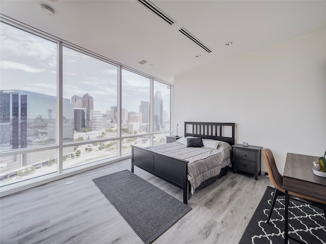 bedroom with multiple windows, wood-type flooring, and a wall of windows