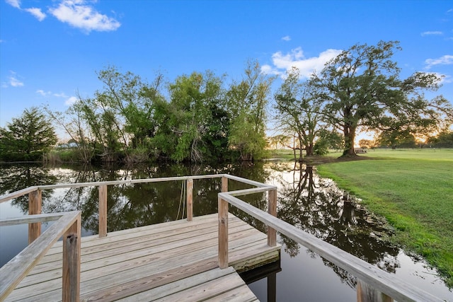 view of dock featuring a lawn and a water view