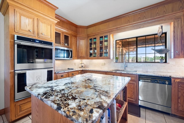 kitchen with light tile patterned flooring, a kitchen island, light stone countertops, and appliances with stainless steel finishes