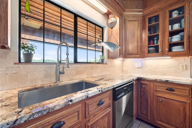 kitchen featuring backsplash, light stone countertops, sink, and stainless steel dishwasher