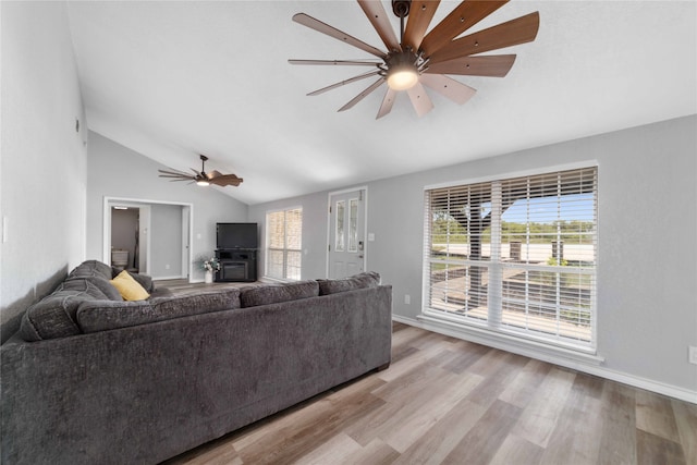 living room featuring ceiling fan, light hardwood / wood-style flooring, a wealth of natural light, and vaulted ceiling