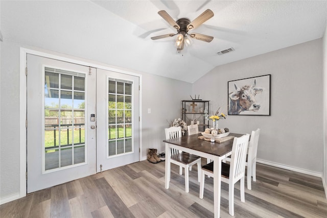 dining room with french doors, a textured ceiling, wood-type flooring, ceiling fan, and vaulted ceiling