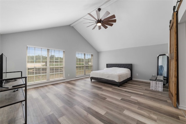 bedroom with beamed ceiling, hardwood / wood-style floors, a barn door, high vaulted ceiling, and ceiling fan